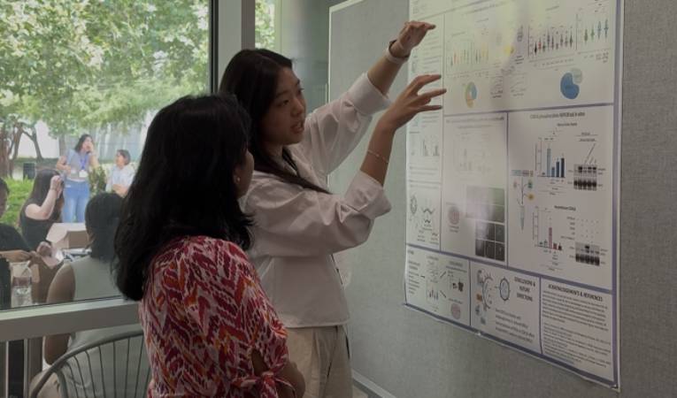 Genetics & Epigenetics student Heather Tsong and one of the judges standing by Heather's poster and talking about it.