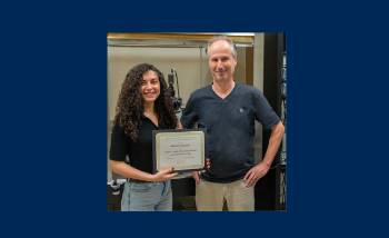 woman with dark hair holding a plaque standing next to man in dark blue shirt