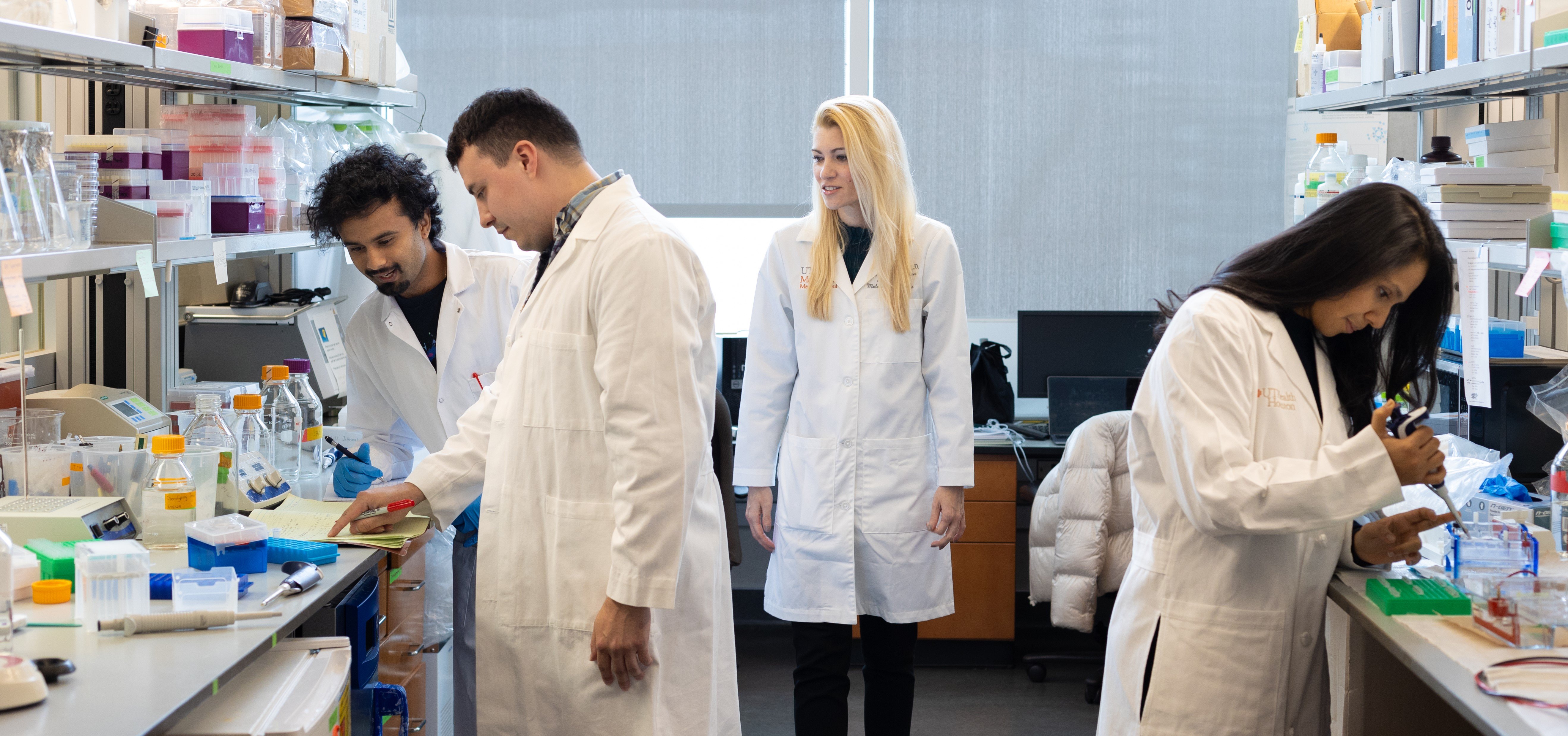 Kendra Carmon, PhD, and 3 students working in a lab
