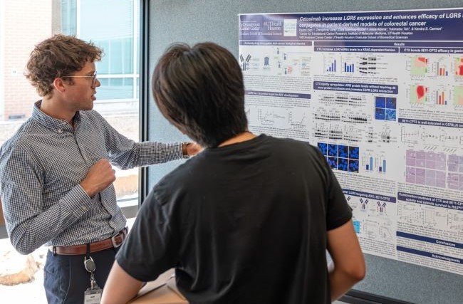 High and another student standing while High presents his poster at the MD Anderson UTHealth Houston Graduate School 2025 Graduate Student Research Day.
