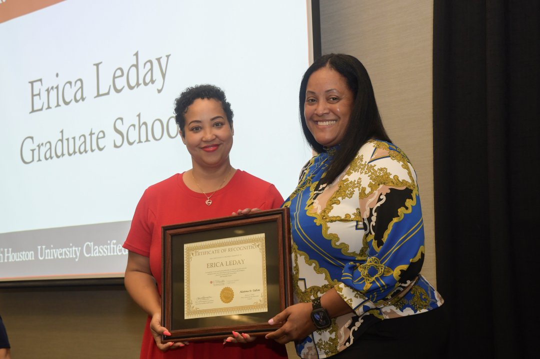 two women smiling as one presents the other with an award