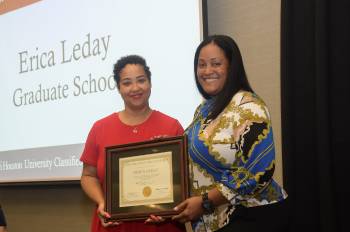 two women smiling as one presents the other with an award