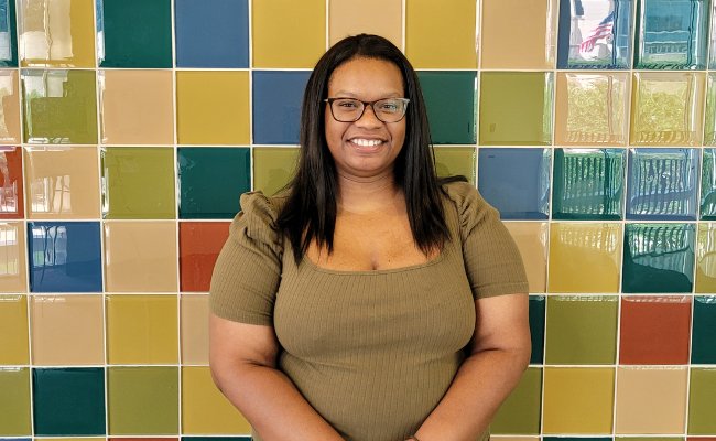 Woman smiling in front of a multicolored tile wall