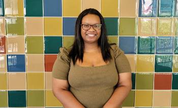 Woman smiling in front of a multicolored tile wall