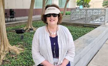 Woman in a sun visor and sunglasses sitting outdoors