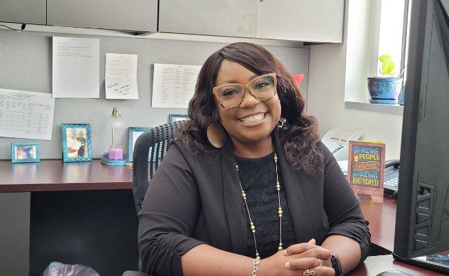 Smiling woman in glasses sitting at a desk