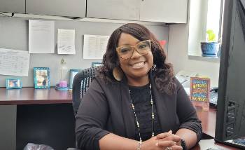 Smiling woman in glasses sitting at a desk