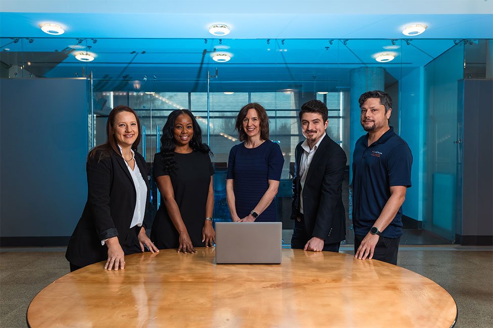 Five UTHealth Houston employees standing behind a table with a laptop on it. (Photo by UTHealth Houston)