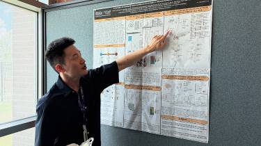 Chia Hsin (Alex) Lin pointing, presenting his poster to a judge.