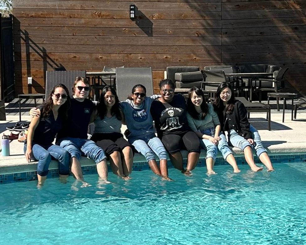 Nayak and friends at a Genetics and Epigenetics retreat sitting by the pool with their feet in the water.