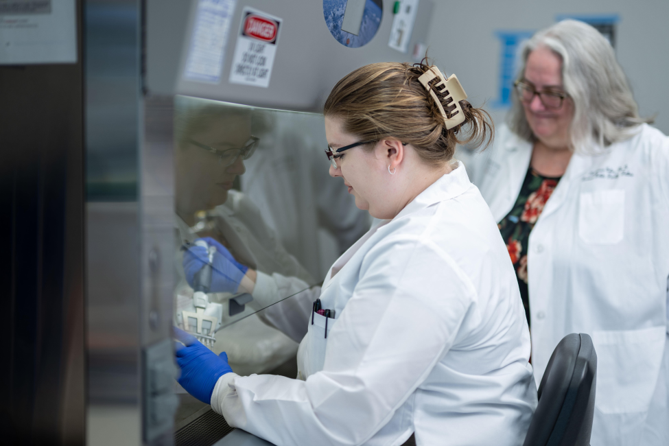 Frasca sitting, working in the lab with her mentor, Francesca Cole, PhD, next to her.
