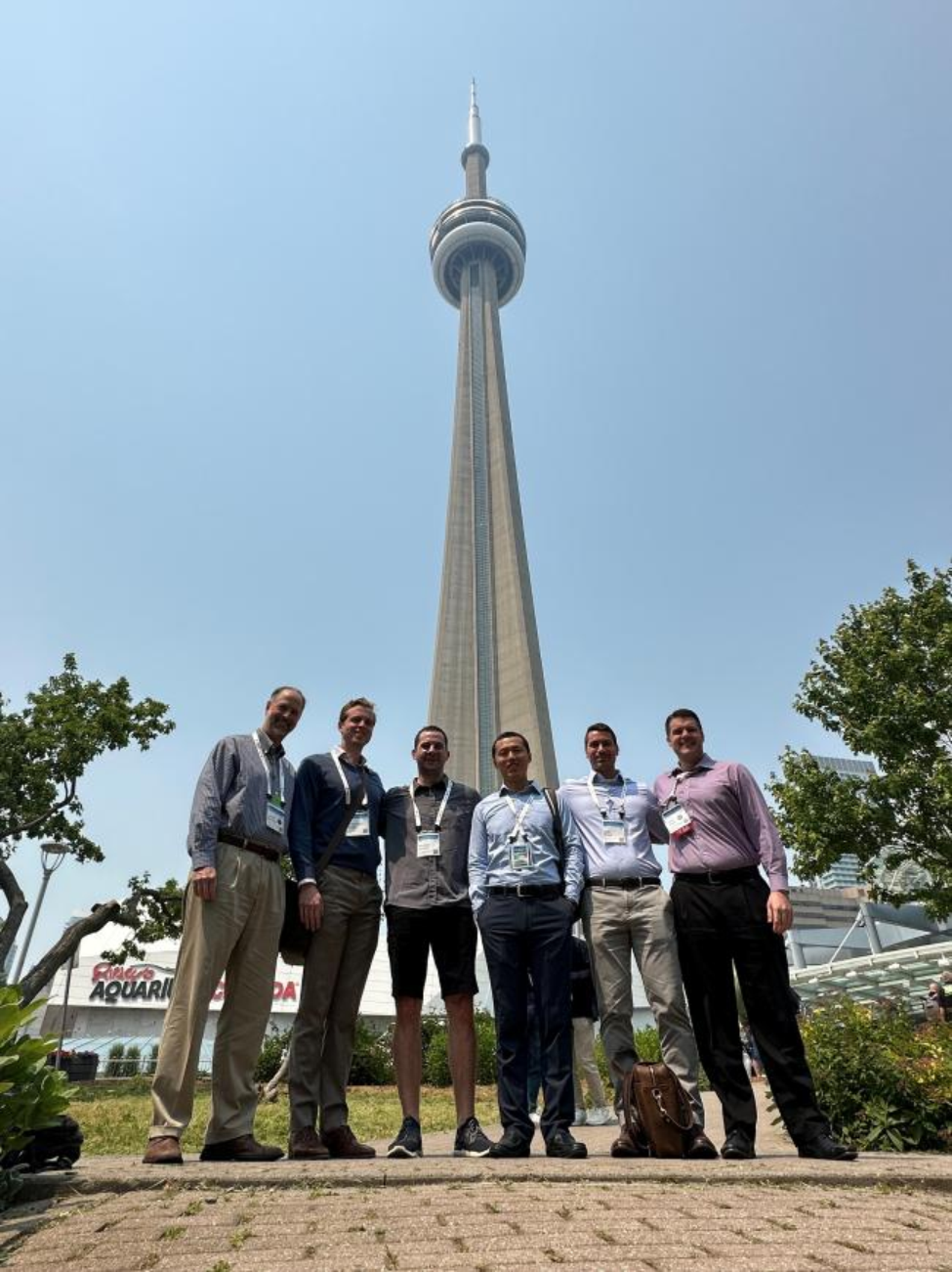 Harlan (far right) standing with lab mates standing in front of the  in front of the CN Tower a.k.a. the Toronto Needle while at the International Society for Magnetic Resonance in Medicine conference in Toronto