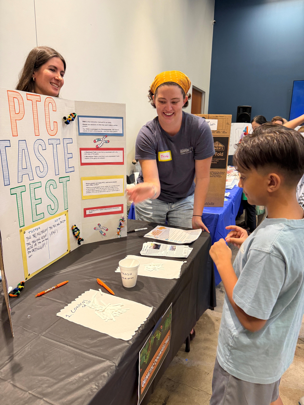 Scarlett demonstrates a hands-on science station to a young boy at Science Night 2025.