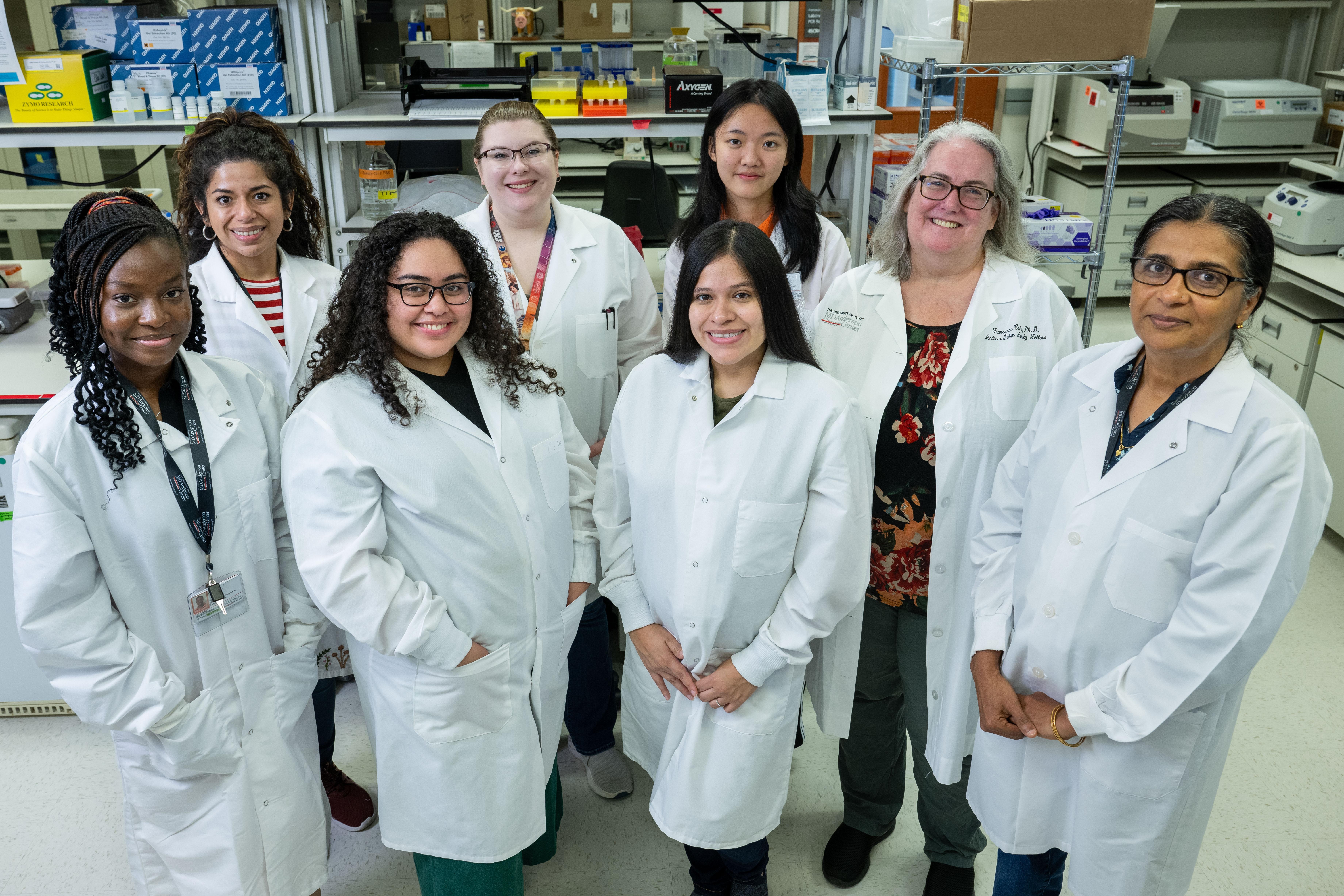 Group of UTHealth Houston researchers and students in lab coats standing together in a laboratory